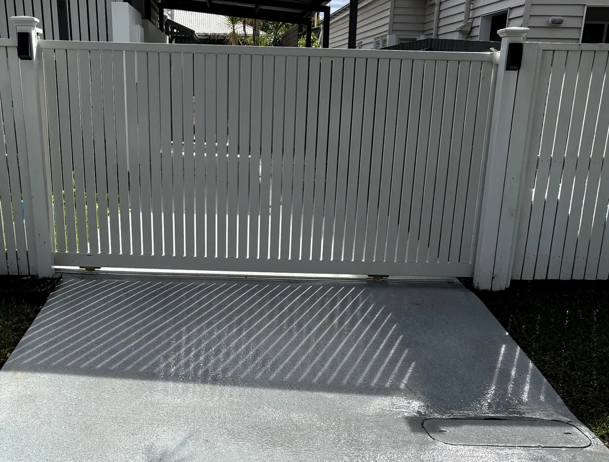 Driveway gate and concrete after pressure washing — bright white and clean